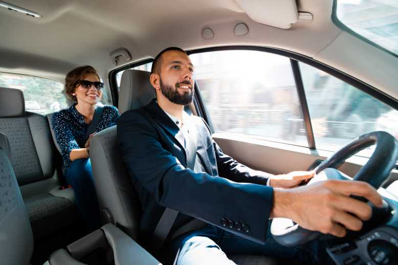 Conducteur souriant parlant avec une femme d'affaires élégante.