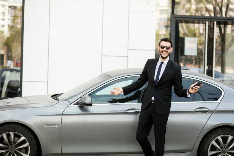 conducteur en costume élégant devant une voiture de luxe