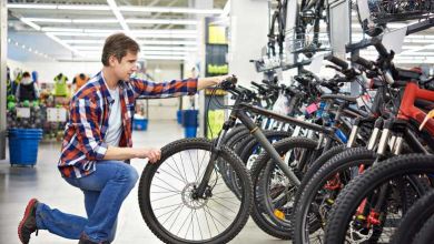 Père avec un adolescent demandant de l'aide à une vendeuse positive pour un magasin de vélo de sport