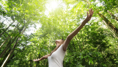 Profiter de la nature. Jeune femme bras levée savourant l'air frais dans la forêt verte.