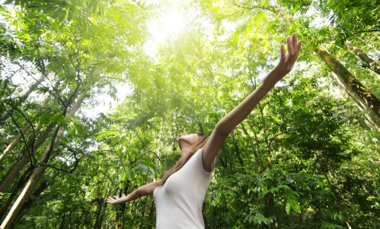 Profiter de la nature. Jeune femme bras levée savourant l'air frais dans la forêt verte.