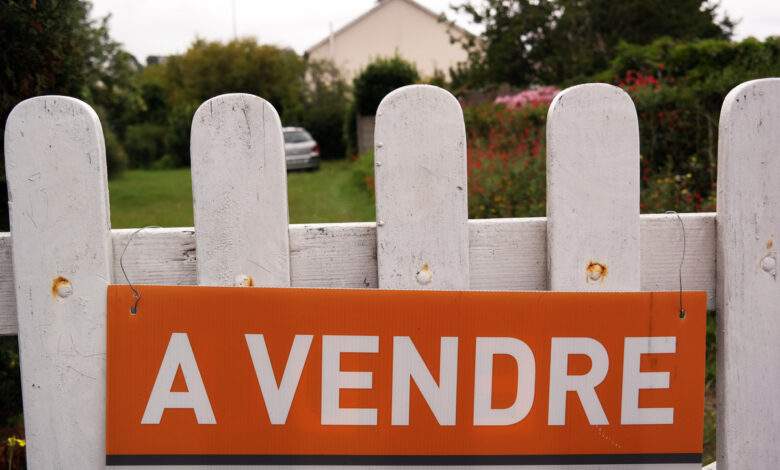 Une maison avec un panneau à vendre