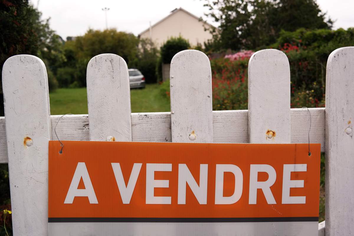 Une maison avec un panneau à vendre