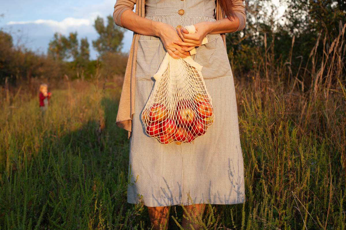 fille en robe tenant un sac à cordes avec des pomme