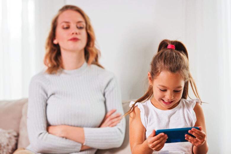 Petite fille utilisant un smartphone, pendant que sa maman