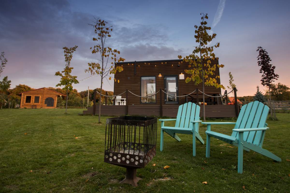 heminée et chaises turquoise devant une minuscule maison sur roues