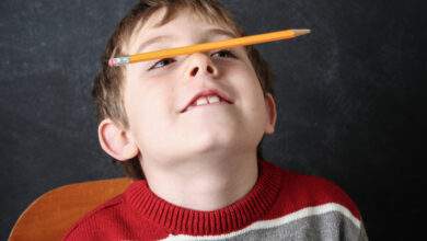 Jeune garçon qui fait le clown avec un crayon en équilibre sur son nez.