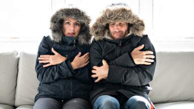 Les couples ont froid sur le canapé à la maison avec leur manteau d'hiver