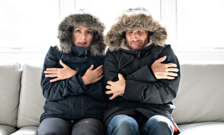 Les couples ont froid sur le canapé à la maison avec leur manteau d'hiver
