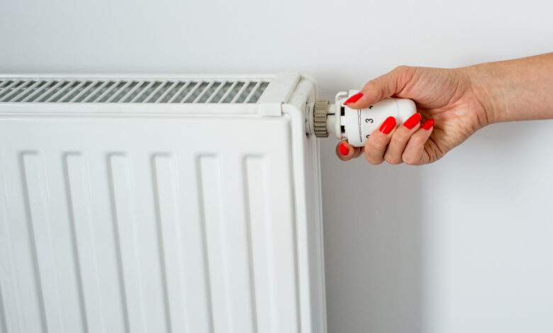Une main féminine sur le thermostat d'un chauffage