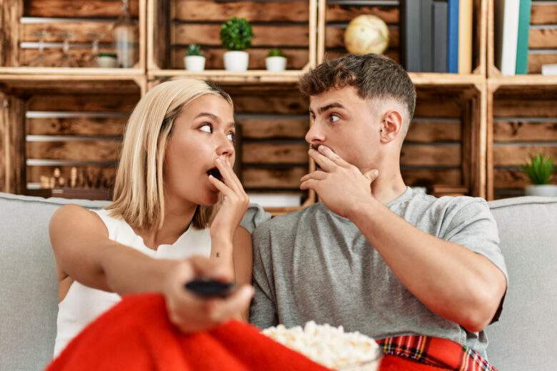 Un jeune couple regarde un film d'horreur à la maison.