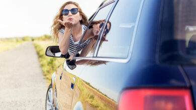 Une jolie femme souriante envoie un baiser aérien depuis la fenêtre de la voiture