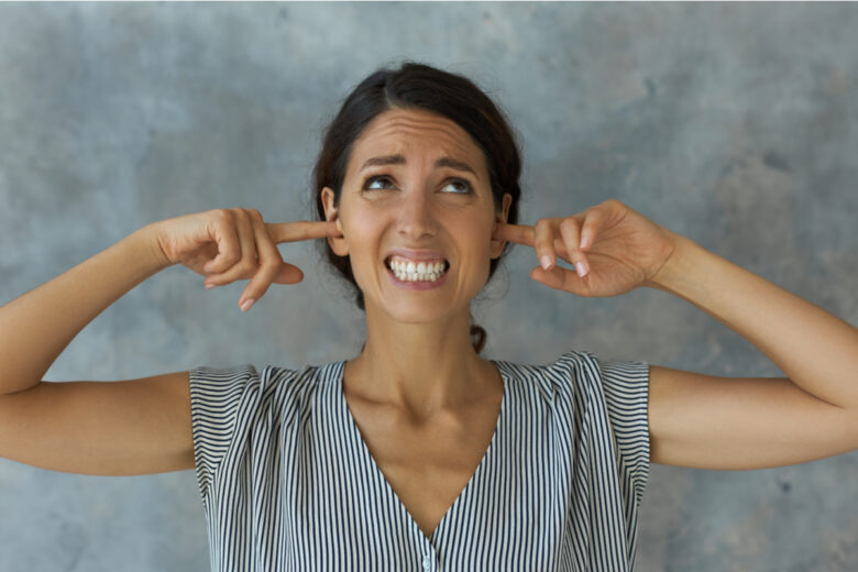 Jeune femme se bouchant les oreilles avec les doigts