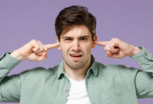Jeune homme se bouchant les oreilles avec les doigts