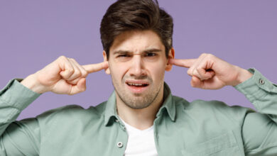 Jeune homme se bouchant les oreilles avec les doigts