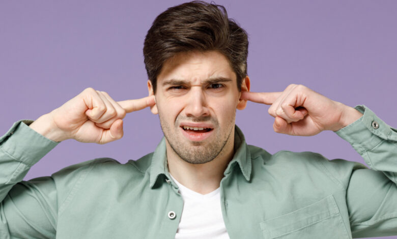 Jeune homme se bouchant les oreilles avec les doigts