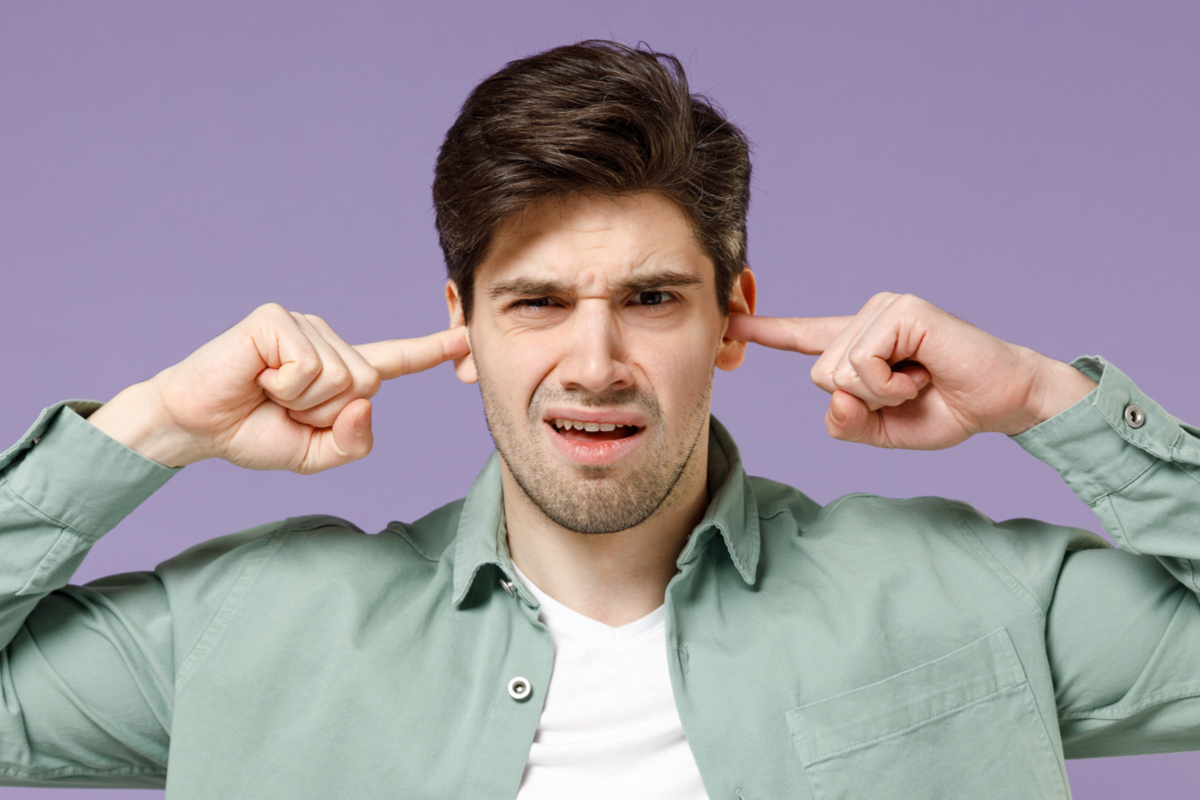 Jeune homme se bouchant les oreilles avec les doigts