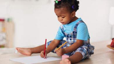 Petite fille qui dessine avec les deux mains.