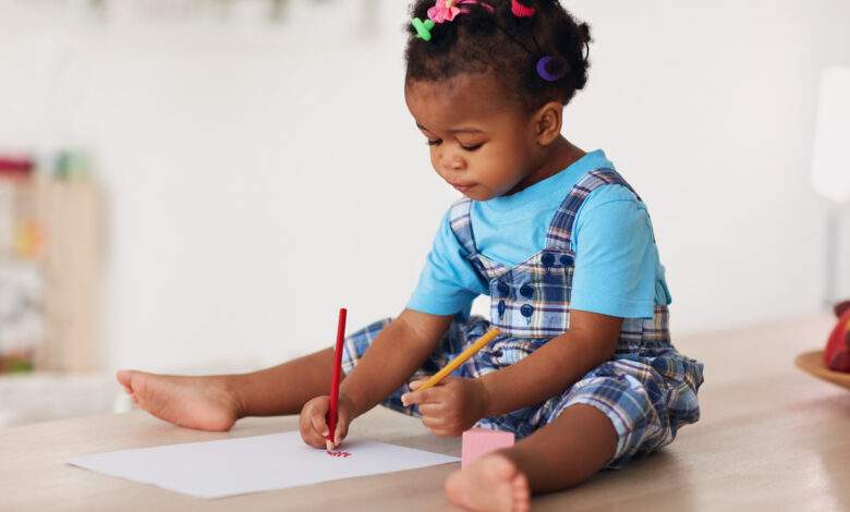 Petite fille qui dessine avec les deux mains.