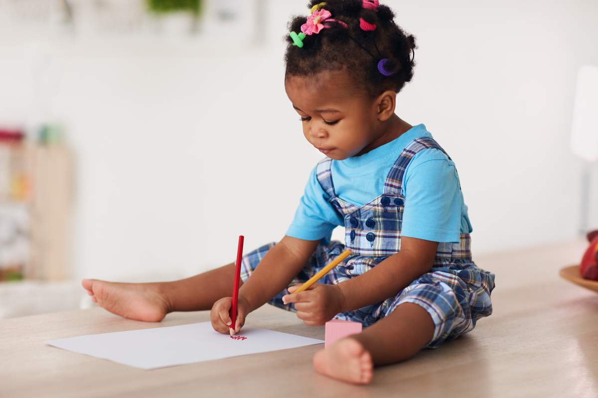 Petite fille qui dessine avec les deux mains.