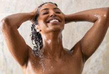 Jeune femme se lavant les cheveux dans la douche