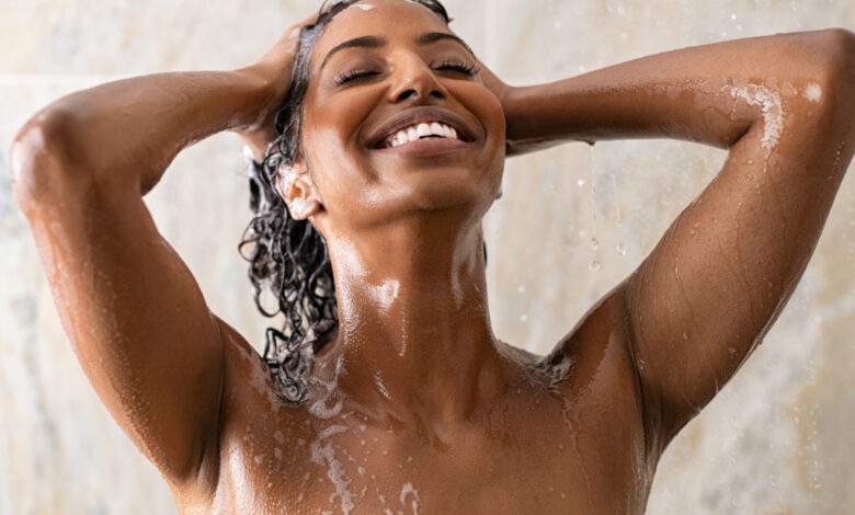 Jeune femme se lavant les cheveux dans la douche
