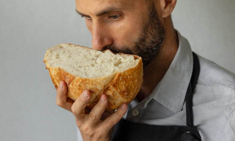 Un boulanger tient un pain frais rond dans les mains