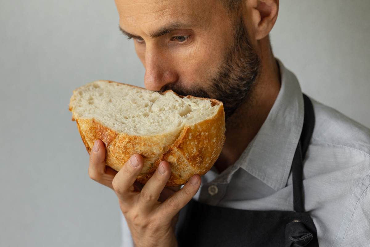 Un boulanger tient un pain frais rond dans les mains