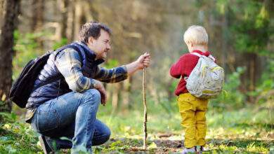 Le père et son petit fils marchant pendant les activités de randonnée dans la forêt automnale au coucher du soleil