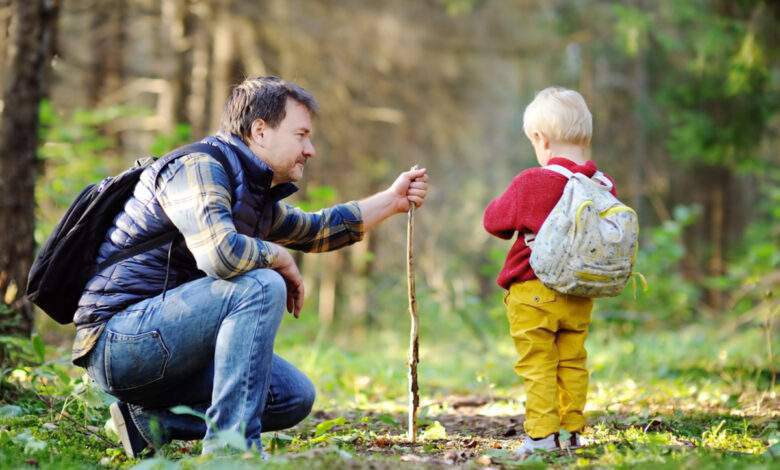 Le père et son petit fils marchant pendant les activités de randonnée dans la forêt automnale au coucher du soleil