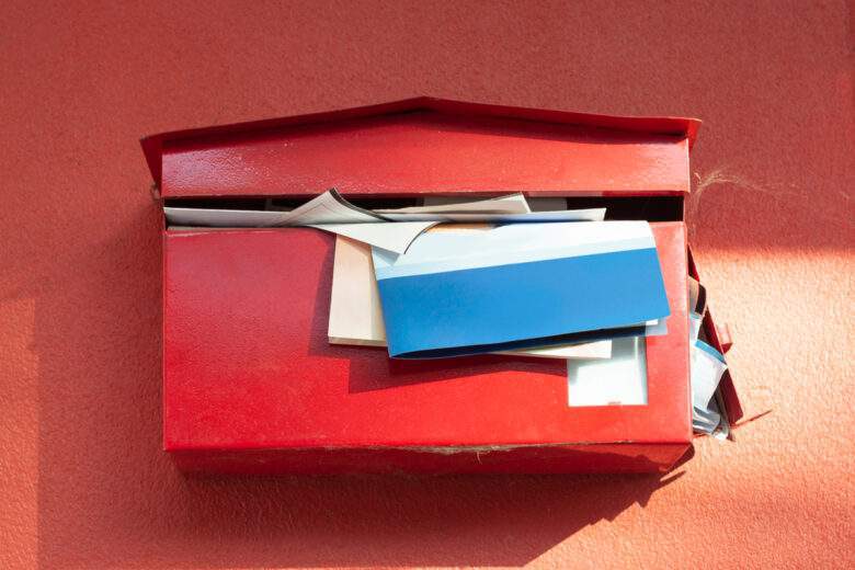 Boîte aux lettres rouge avec documents débordant,