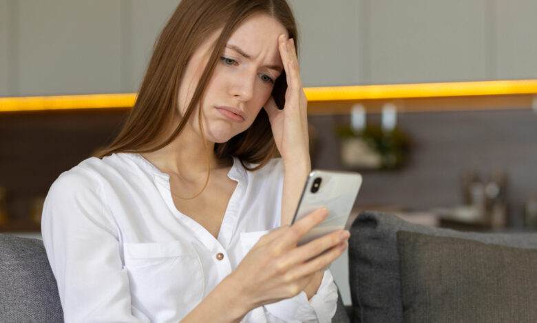 Une jeune femme fait la grimace en lisant un message sur Tinder.
