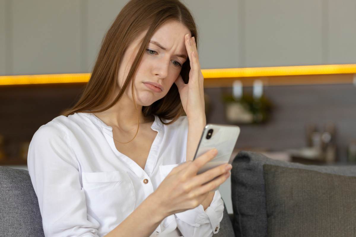 Une jeune femme fait la grimace en lisant un message sur Tinder.