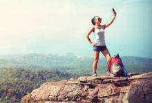 Randonneur femme prenant une photo avec un téléphone intelligent au sommet de la montagn