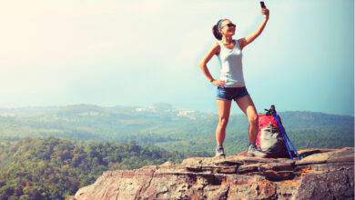 Randonneur femme prenant une photo avec un téléphone intelligent au sommet de la montagn