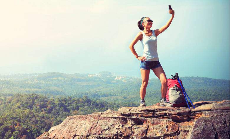 Randonneur femme prenant une photo avec un téléphone intelligent au sommet de la montagn