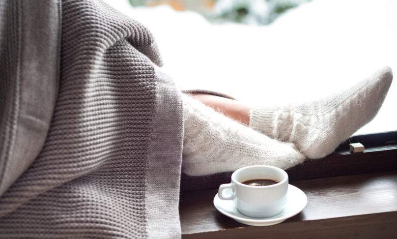 Pieds féminins dans des chaussettes chaudes en laine d'hiver et recouvertes d'une couverture
