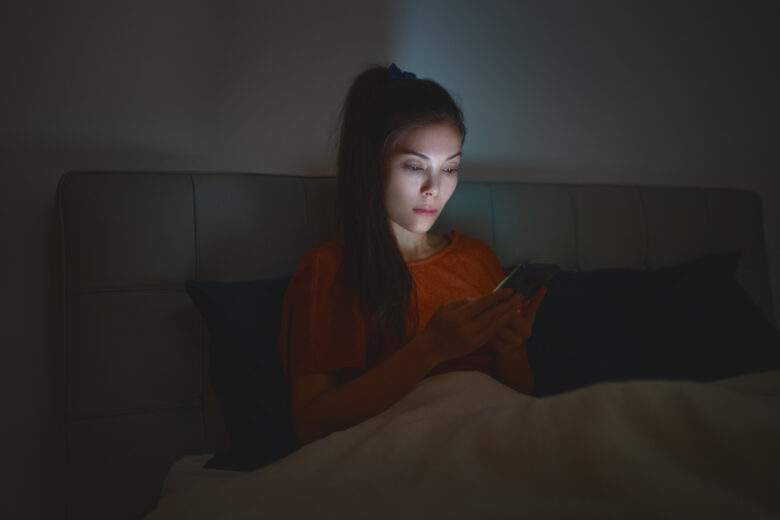 Une femme qui dort avec son téléphone au lit