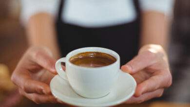 Une serveuse offre une tasse de café au café