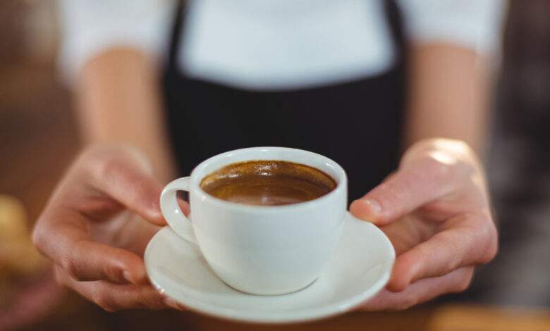 Une serveuse offre une tasse de café au café