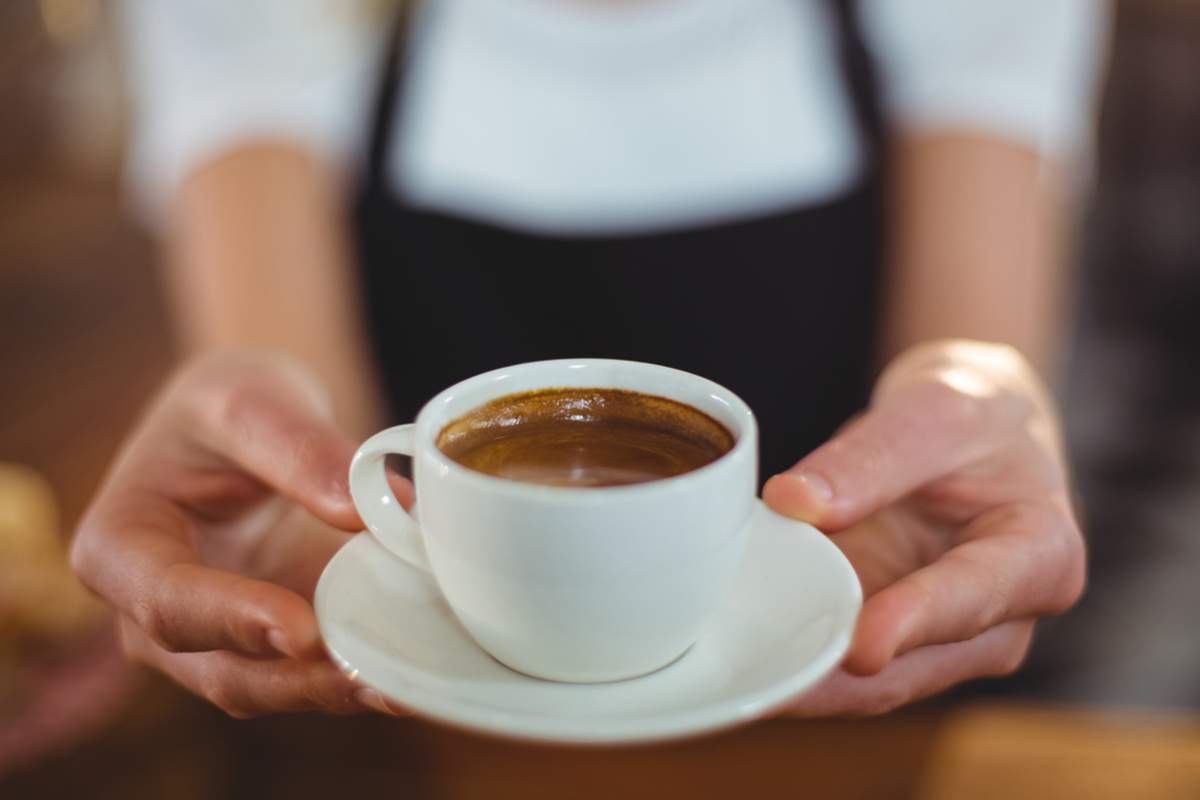 Une serveuse offre une tasse de café au café