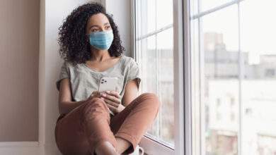 Une femme devant sa fenêtre pendant le confinement