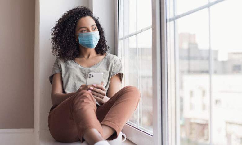 Une femme devant sa fenêtre pendant le confinement
