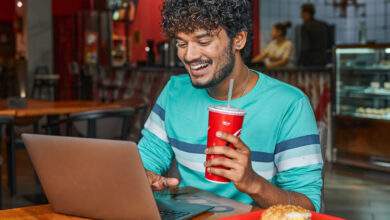 un jeune homme boit du sodas dans un fast food