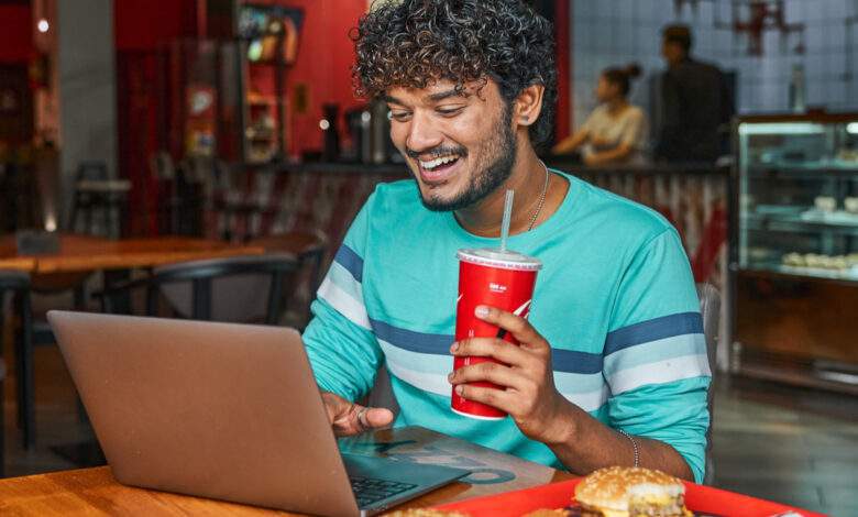 un jeune homme boit du sodas dans un fast food
