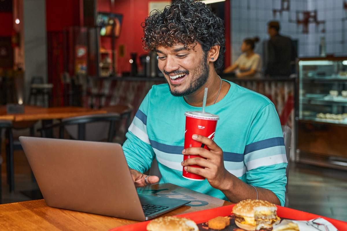 un jeune homme boit du sodas dans un fast food