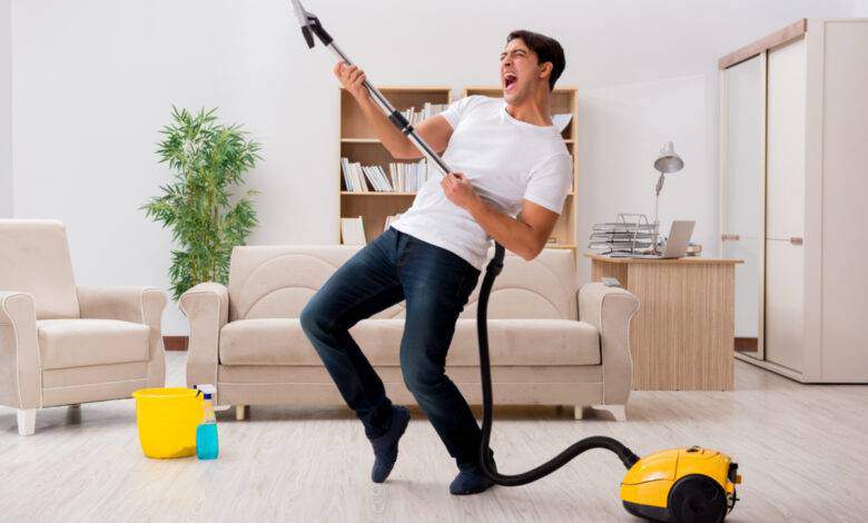 Homme nettoyant sa maison avec aspirateur