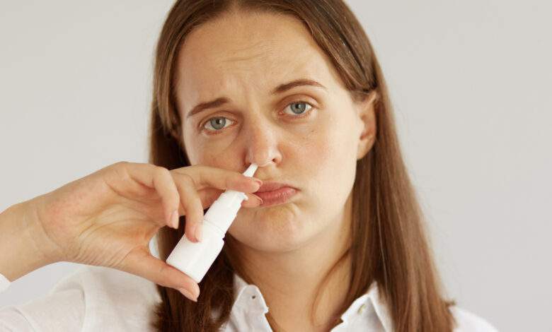 femme avec un spray nasal dans le nez