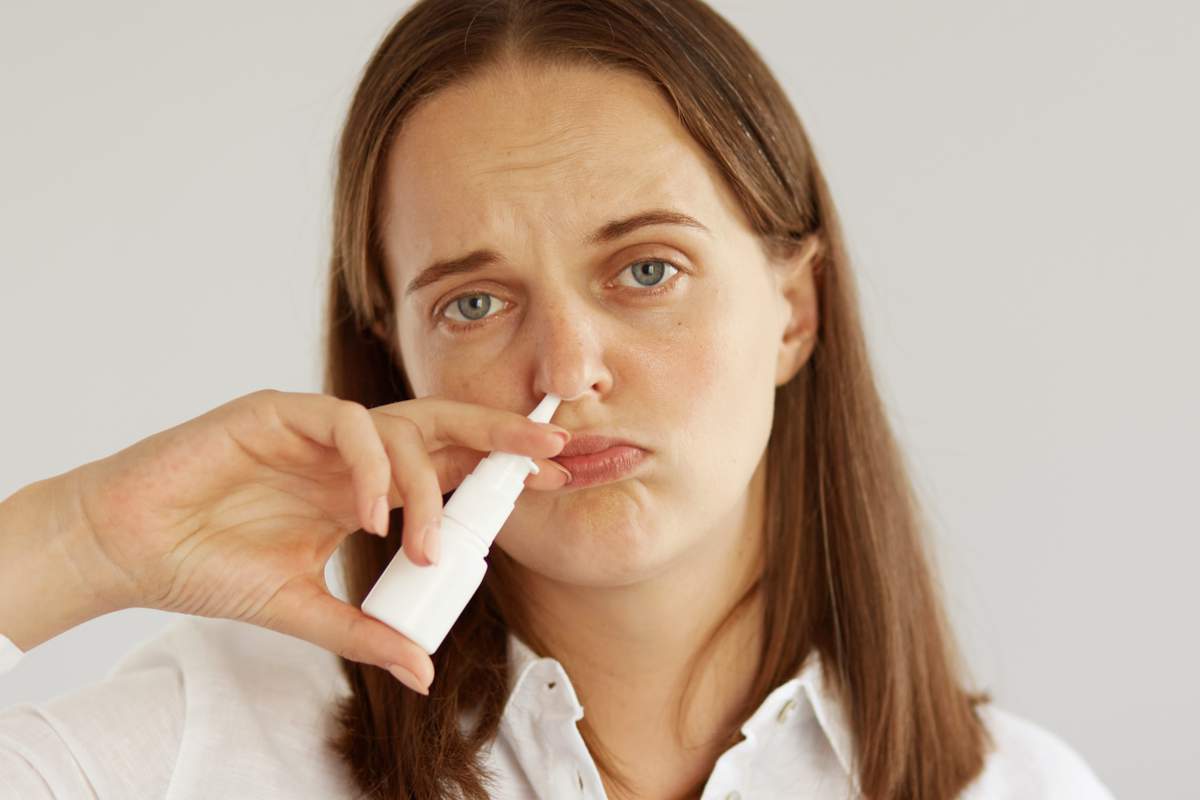 femme avec un spray nasal dans le nez