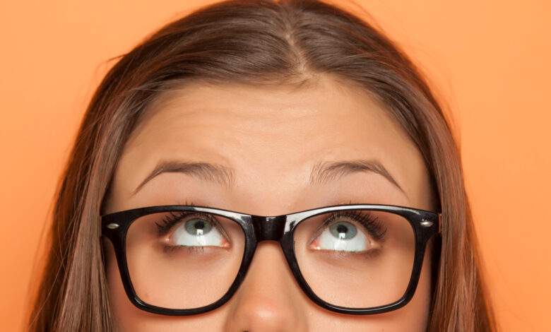 demi-portrait d'une jeune fille avec lunettes levant les yeux